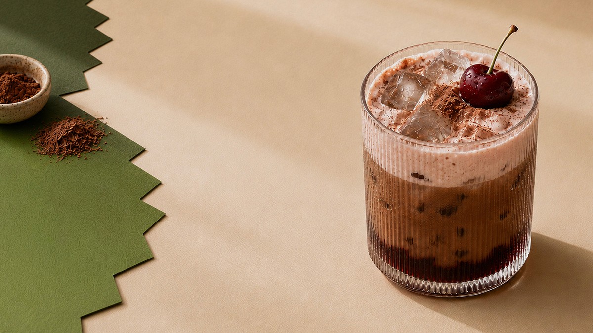 Iced mocha topped with fluffy foam, chocolate shavings, and a fresh cherry.